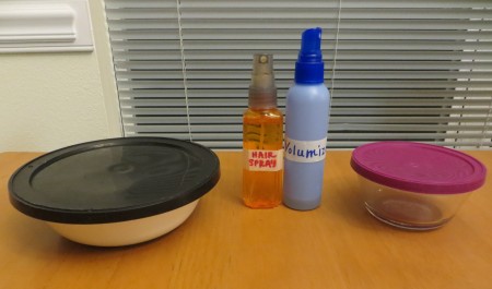 Two bowls with lids and two spray bottles.