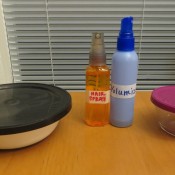 Two bowls with lids and two spray bottles.