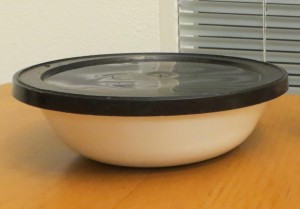 A glass bowl with a black lid.