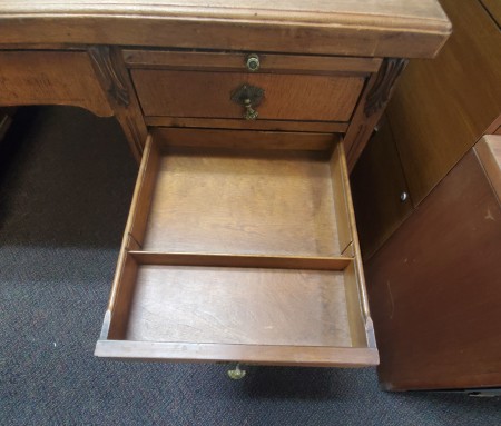 The open drawer of a wooden desk.