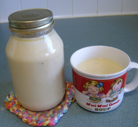 A cup of soup next to a mason jar filled with the leftover soup.