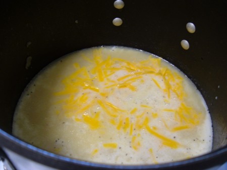 Adding cheese to the soup mixture.