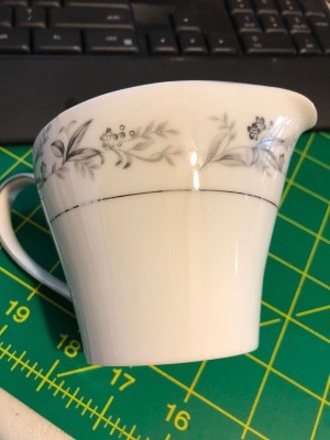 A china creamer with a grey pattern.