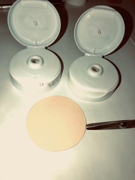 The cut out circle of paper next to the lids.