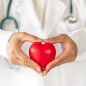 A doctor holding a red heart.