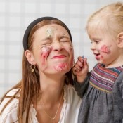 A mother and child playing with face paint.