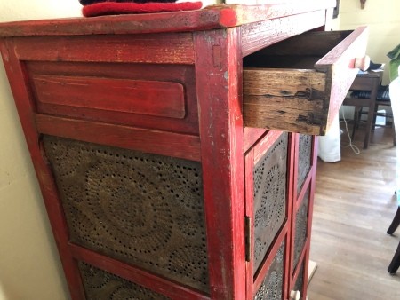 The side view of a pie safe with an open drawer.
