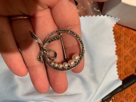 A silver brooch with pearls.