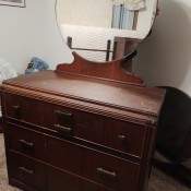 A dresser with a round mirror.
