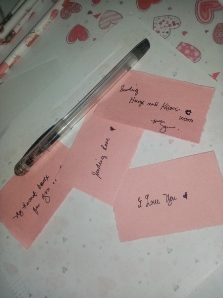 Writing love notes on pink paper.