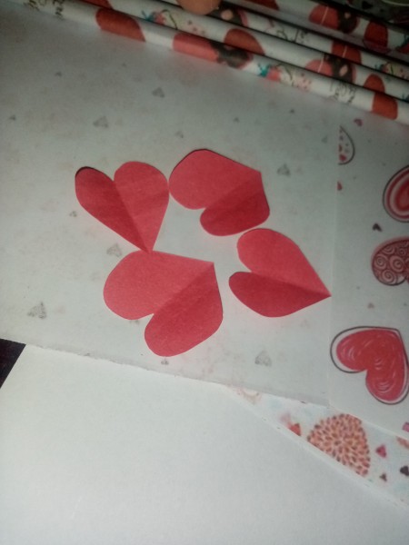 Making red hearts cut out of paper.