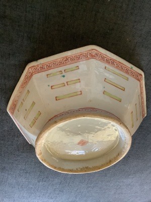 A cream colored octagonal ceramic bowl with red markings.