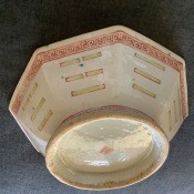 A cream colored octagonal ceramic bowl with red markings.