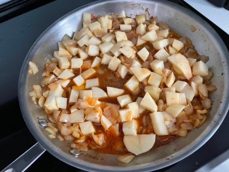 Adding the potatoes to the pan.