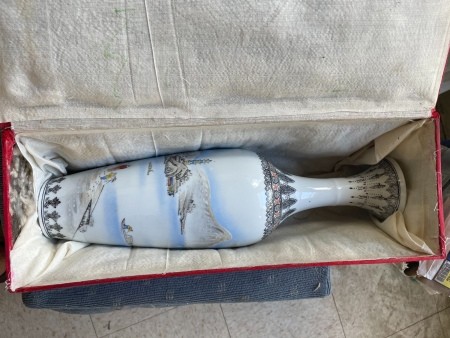 A painted china vase in a box.
