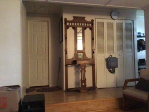A wooden hall stand with a small mirror.