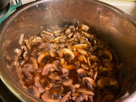 Adding the broth to the mushrooms.