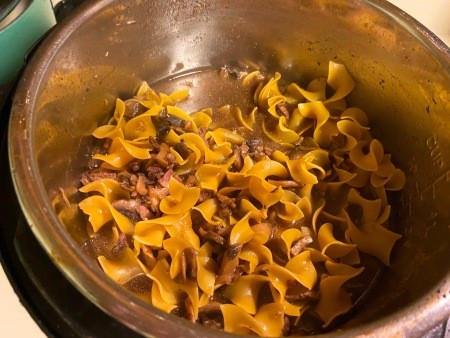 Adding the egg noodles to the pot.