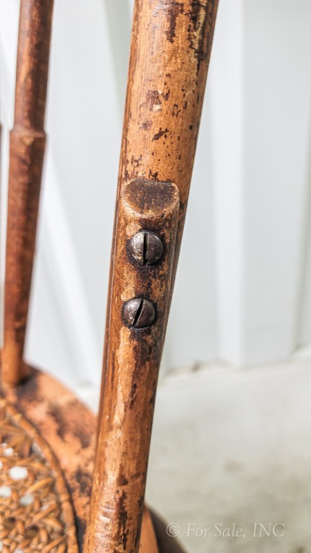 Old screws connecting the back of the wooden chair.