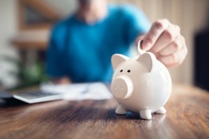 A person putting a coin in a piggy bank.