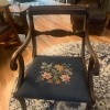 An old wooden chair with an embroidered seat.