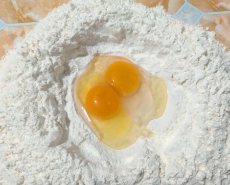 Adding eggs to flour.
