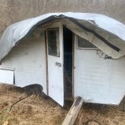 An old camper covered with a tarp.