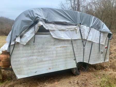An old camper covered with a tarp.