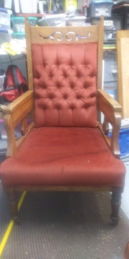 An old chair with reddish upholstery.