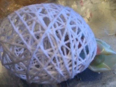 Removing the eggshell to leave the empty yarn egg.