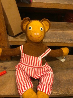 A stuffed monkey wearing striped overalls.
