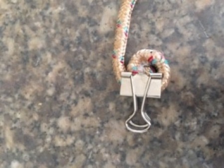 Attaching a binder clip to the end of a rope.