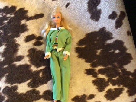 A Barbie doll wearing a green pantsuit.