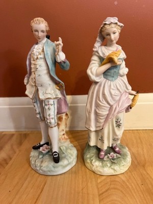 Two figurines dressed in old fashioned clothing.