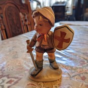 A small figurine of a boy with a shield and sword.
