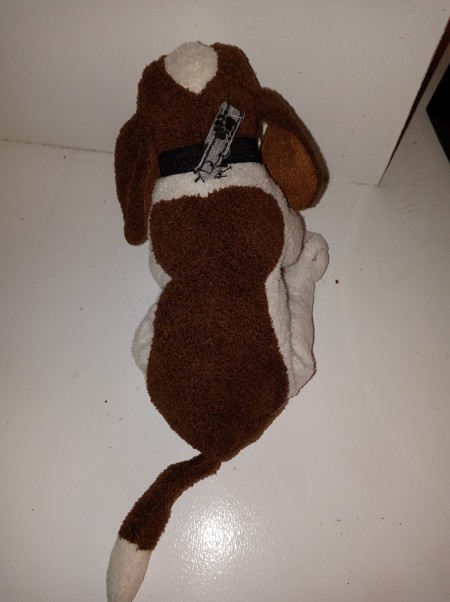 A brown and white stuffed dog, from the back.