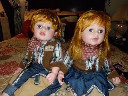 Two red headed porcelain dolls in matching country outfits.