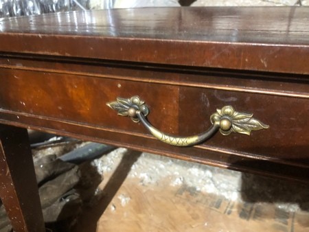 A drawer on a wooden desk.