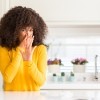 A woman smelling a rotten odor in the kitchen.