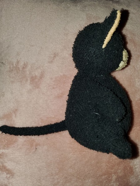 A black and cream stuffed kitty, side view.