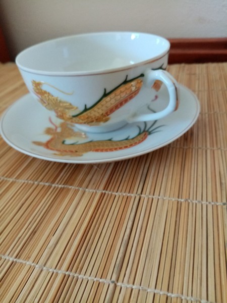 A tea cup and saucer with a painted dragon.