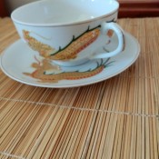A tea cup and saucer with a painted dragon.