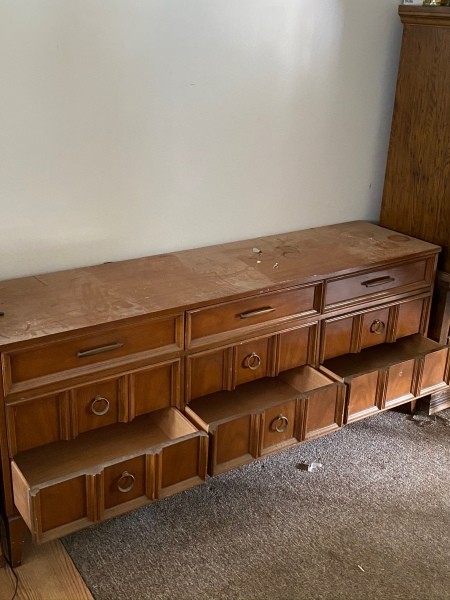 A long wooden dresser with the bottom drawers open.