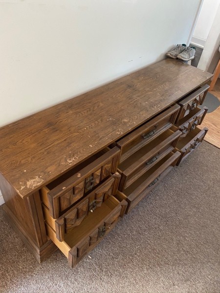 A long wooden dresser with all the  drawers open.