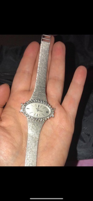A silver women's watch with gemstones around the face.