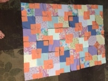 The baby quilt laid out in the correct pattern.