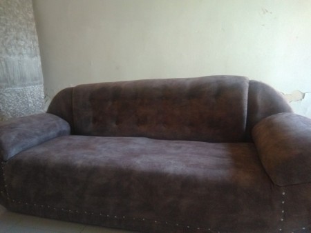 A brown couch without throw pillows.