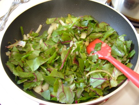 Stir frying beet greens in a pan.