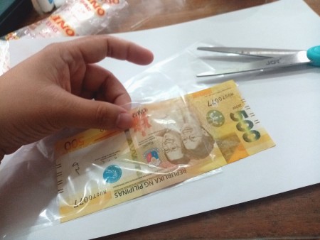 Placing money inside the plastic.