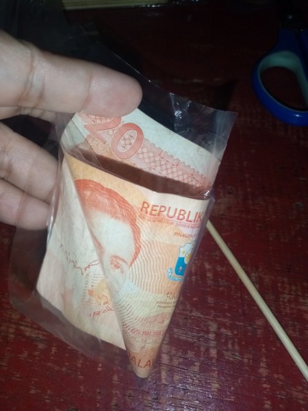 Curling the money into a cone.